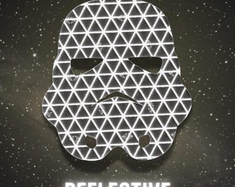May include: A stormtrooper helmet-shaped decal featuring a repeating white triangular grid pattern on a black background. The word REFLECTIVE is printed in white capital letters below the helmet shape, which has cutouts for eyes and mouth.