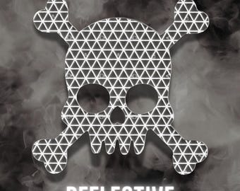 May include: A skull and crossbones decal featuring a silver reflective geometric triangle pattern. The design is centered and includes the word REFLECTIVE in white capital letters positioned directly below the skull and crossbones graphic.