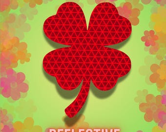 May include: A red reflective four-leaf clover design with a geometric pattern, set against a light green background with floral accents. The word "REFLECTIVE" is displayed in white text.