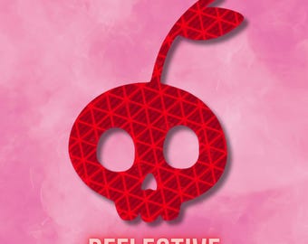 May include: A red reflective decal featuring a stylized skull shaped like a cherry with a single leaf on top. The surface of the graphic has a repeating triangular grid pattern. The word REFLECTIVE is printed in bold red capital letters below the icon.