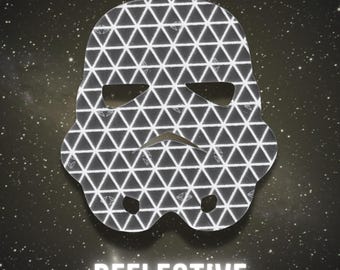 May include: A reflective Stormtrooper helmet design with a geometric pattern. The helmet is black and white, with a triangular pattern. The word "REFLECTIVE" is displayed in white, below the helmet, against a starry background.