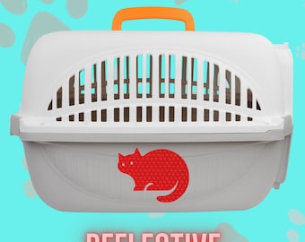 May include: A white plastic pet carrier featuring an orange top handle and a large arched ventilation window. A red reflective cat-shaped decal is centered on the front panel. The word REFLECTIVE is printed in large pink letters below the carrier.