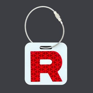 May include: A square white luggage tag featuring a large, bold, reflective red letter R with a geometric triangular pattern. The tag is attached to a flexible, silver-toned braided metal cable loop with a threaded cylindrical screw-top closure.
