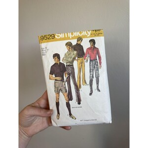 May include: A vintage Simplicity sewing pattern envelope, number 9529, featuring illustrations of various pants and shorts styles. The white paper envelope displays the text 9529, Simplicity, and size 30, waist 30, hip 37, with illustrations of four figures wearing different outfits.