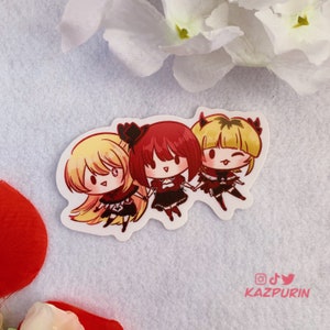 Peut inclure: Trois filles de dessin animé en tenues rouges et noires se tenant la main. La fille à gauche a les cheveux blonds, la fille du milieu a les cheveux roux et un chapeau noir, et la fille à droite a les cheveux blonds et des cornes de diable. L'autocollant porte le texte "KAZPURIN" en bas.