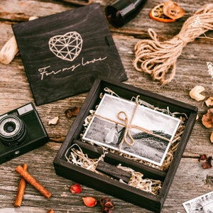 May include: A black wooden box with a lid that says "For my love" in white lettering. The box is open and contains a black and white photograph of a couple standing in a field. The box is surrounded by decorative items, including a camera, cinnamon sticks, and dried flowers.