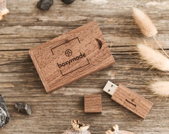 May include: A wooden boxymade USB drive with a wooden box and a USB connector. The drive is on a wooden surface with dried flowers and small stones.