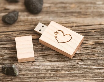 Könnte beinhalten: Ein USB-Stick aus Holz mit einem Herz und dem Wort "love" eingraviert. Der Stick liegt auf einer Holzoberfläche.