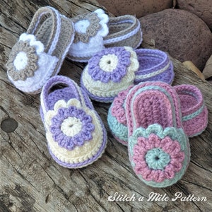 May include: Four pairs of crocheted baby shoes with flower embellishments in various colors, including brown, white, purple, cream, pink, and green. The shoes are displayed on a wooden surface. "Stitch a Mile Pattern" is written on the surface.