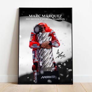 Puede incluir: Póster enmarcado en negro con Marc Márquez abrazando un trofeo. El póster incluye el texto "MARC MÁRQUEZ 2025 MOTOGP WORLD CHAMPION" y una firma. La imagen es en blanco y negro con un toque de color del uniforme rojo del corredor.