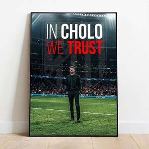 以下が含まれることがあります： 黒いスーツを着た男性が緑のサッカー場に立っている、額入りのポスター。テキスト「IN CHOLO WE TRUST」は白と赤で表示されています。背景には観客でいっぱいのスタジアムが描かれています。