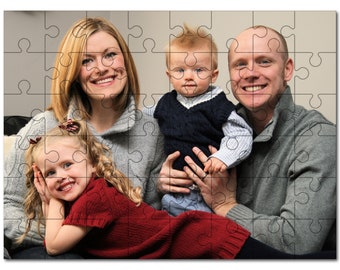 Puede incluir: Un retrato familiar que muestra a una mujer con el pelo largo y rubio, un hombre con el pelo corto y castaño, una niña pequeña con el pelo largo y rubio y un bebé con el pelo rubio. La familia está sentada en un sofá y sonriendo a la cámara. La mujer lleva un jersey gris, el hombre lleva un jersey gris, la niña lleva un jersey rojo y el bebé lleva un jersey azul y una camisa blanca.