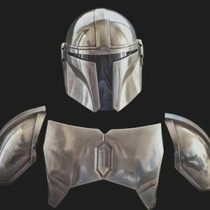 May include: A metallic silver helmet with a T-shaped visor and a matching chest plate with two separate shoulder pauldrons. The armour pieces feature a smooth, reflective finish and geometric contours, presented as a set of costume components.