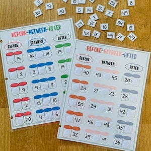 May include: Two educational learning boards with the text "BEFORE-BETWEEN-AFTER" and numbered jars. The boards are designed to teach number sequencing. Small numbered tiles are scattered around the boards.