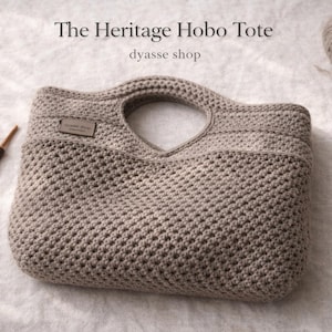Può includere: Borsa hobo beige all'uncinetto con manico e piccola etichetta in pelle. La borsa presenta un motivo ripetuto e strutturato. Sono visibili anche un uncinetto e un gomitolo di lana.