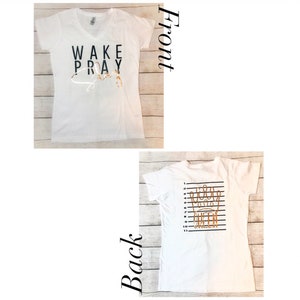 May include: White t-shirt with black text that reads "WAKE PRAY" on the front and a gold crown with the word "QUEEN" on the back.
