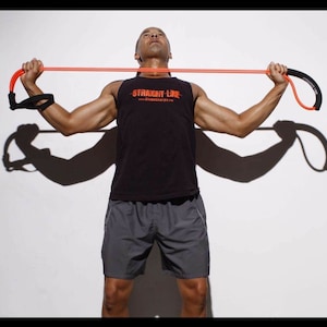May include: A person is using a resistance band to exercise. The band is orange and has a black handle. The person is wearing a black tank top with the text "STRAIGHT LINE" and gray shorts.