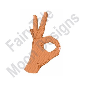 May include: A hand gesture showing the OK sign. The hand is brown and the fingers are curled into a circle.