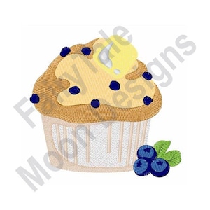 Może przedstawiać: Żółty i brązowy cupcake z niebieskimi borówkami i białym lukrem. Cupcake jest w białym papierowym opakowaniu z brązową obwódką.