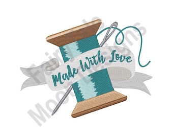 Op de afbeelding: Een turquoise draadspoel met een houten basis en een naald die erdoorheen is geregen. Een wit lint met de tekst "Made with Love" is om de spoel gewikkeld.