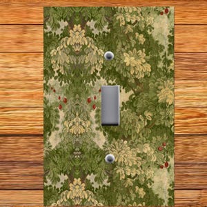 May include: A light switch cover with a vintage floral pattern featuring green, yellow, and red accents. The pattern is reminiscent of a tapestry or wallpaper.
