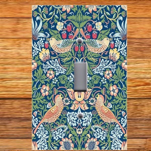 May include: A light switch cover with a floral pattern featuring birds and berries. The design is in shades of blue, green, pink, and yellow.