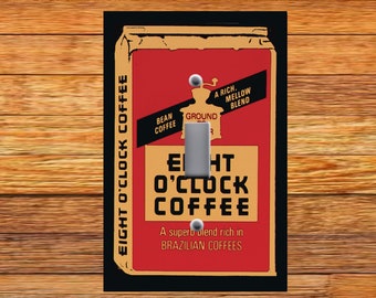 May include: A vintage-style light switch cover featuring a red and brown illustration of an Eight O'Clock Coffee bag. The bag has the text "Eight O'Clock Coffee" and "A superb blend rich in Brazilian Coffees".