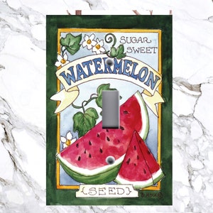 May include: A light switch cover with a vintage-style illustration of a watermelon seed packet. The packet is green with a yellow border and features a red and green watermelon with the words "Sugar Sweet Watermelon Seed" printed on it.