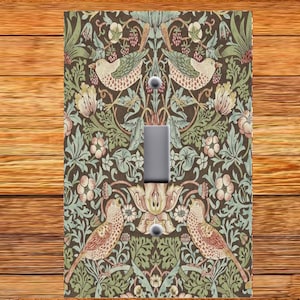 May include: A light switch cover with a vintage floral pattern featuring birds and leaves in shades of green, brown, pink, and blue.
