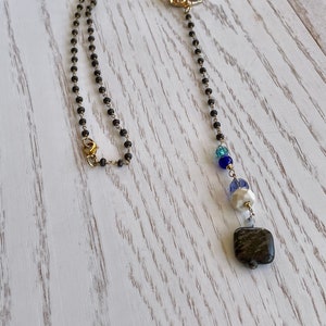 Gold wrapped  dark charcoal pyrite rosary chain, amythyst gold Druzy focal bead, and a dangle of dark greek dyed Jasper, and blue crystals
