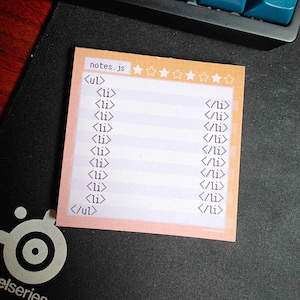 Może przedstawiać: Różowa karteczka samoprzylepna z siatką i pięcioma gwiazdkami u góry. Na karteczce widnieje tekst "notes.js" i kod HTML dla nieuporządkowanej listy z elementami listy.