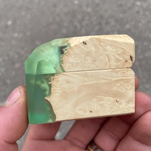 Peut inclure: Petite boîte en bois avec un accent en résine vert clair. La boîte est faite de bois de couleur claire avec un motif de grain naturel. La résine est de couleur verte translucide. La boîte est rectangulaire avec un couvercle à charnière.