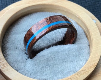 May include: A wooden ring with a blue inlay. The ring is in a small wooden box with a gray velvet lining.