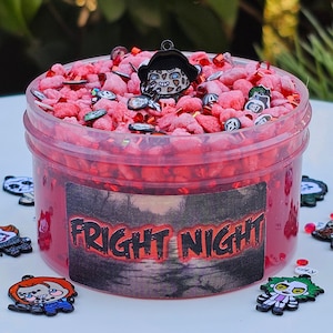 May include: A red slime with a clear container and a black label that says "FRIGHT NIGHT". The slime is topped with red and white sprinkles and a black charm of a horror movie character.
