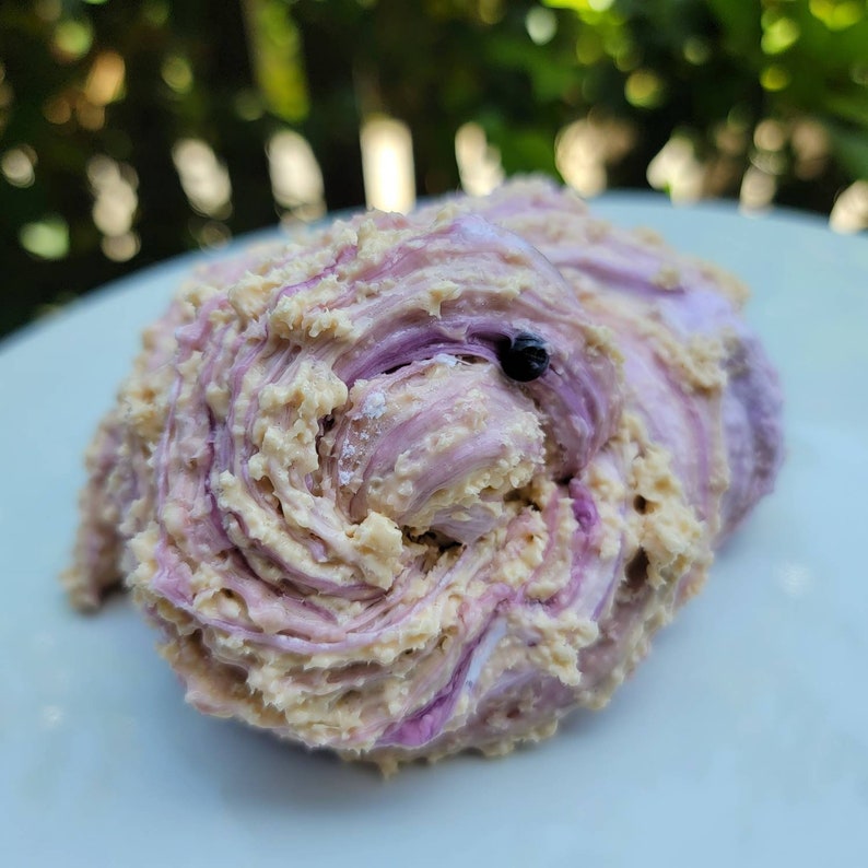 May include: A close-up of a swirl of purple and beige frosting, possibly a cake or cupcake topping.
