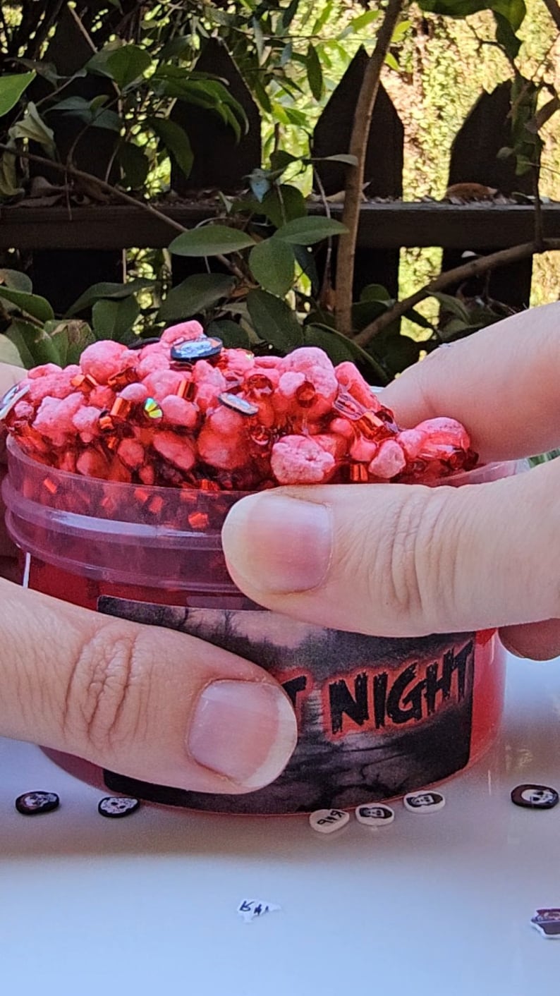May include: A red slime with red and gold glitter in a clear plastic container with a black and red label that says "Fright Night".