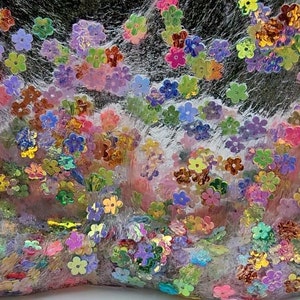 May include: Clear slime with iridescent flower-shaped glitter. The slime is a light pink colour and the glitter is a mix of colours, including pink, blue, green, and gold.