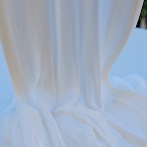 May include: White slime with a smooth, glossy texture. The slime is draped over a surface, creating folds and wrinkles.