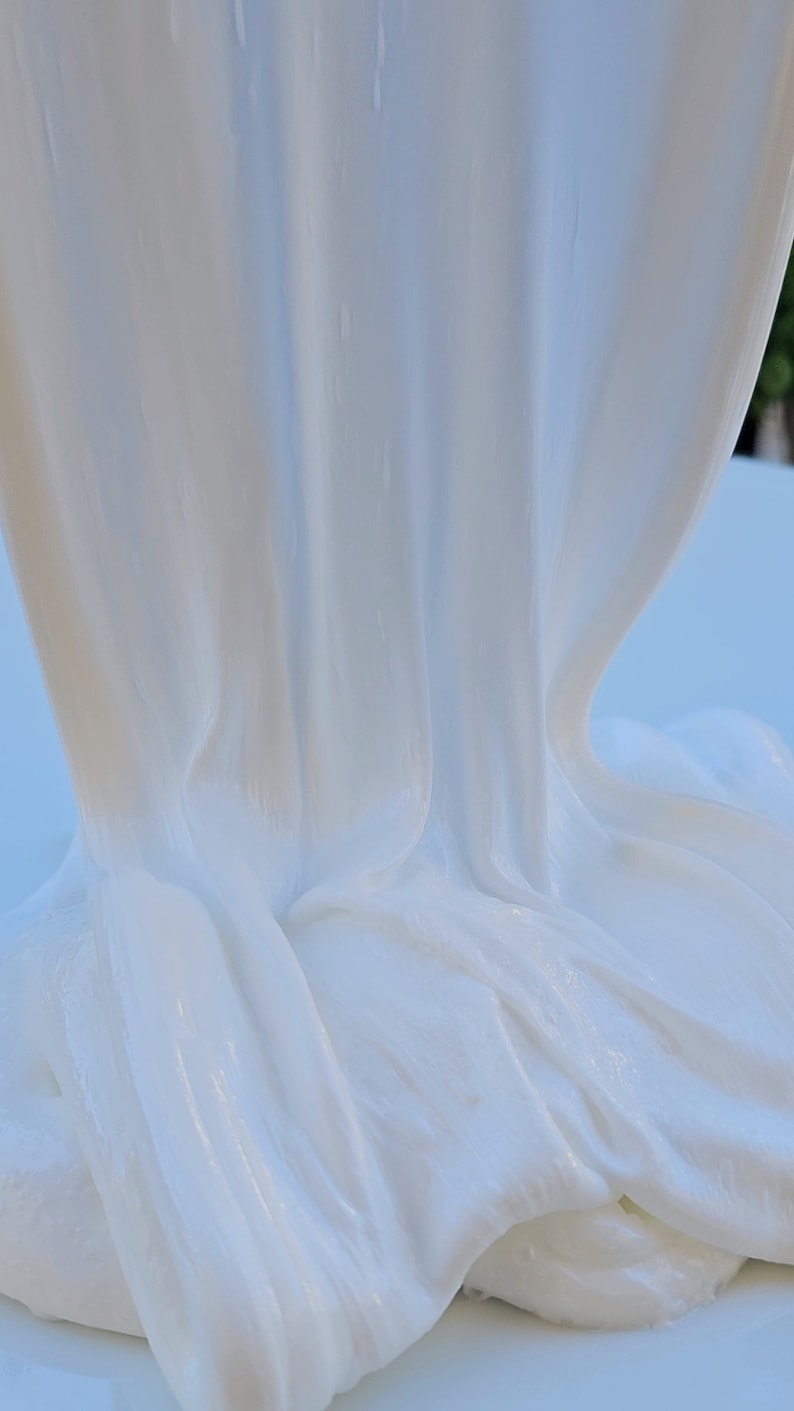 May include: White slime with a smooth, glossy texture. The slime is draped over a surface, creating folds and wrinkles.