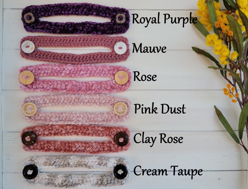 Op de afbeelding: Zes gehaakte gezichtsmasker-verlengstukken in verschillende tinten roze, paars en cr&egrave;me. De kleuren zijn gelabeld met "Royal Purple", "Mauve", "Rose", "Pink Dust", "Clay Rose" en "Cream Taupe".