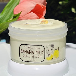 May include: A white jar with a yellow lid and a white label that says "Crafty Farms Banana Milk Grade A | Vit A & D Do Not Eat" with a cartoon cow and banana illustration.