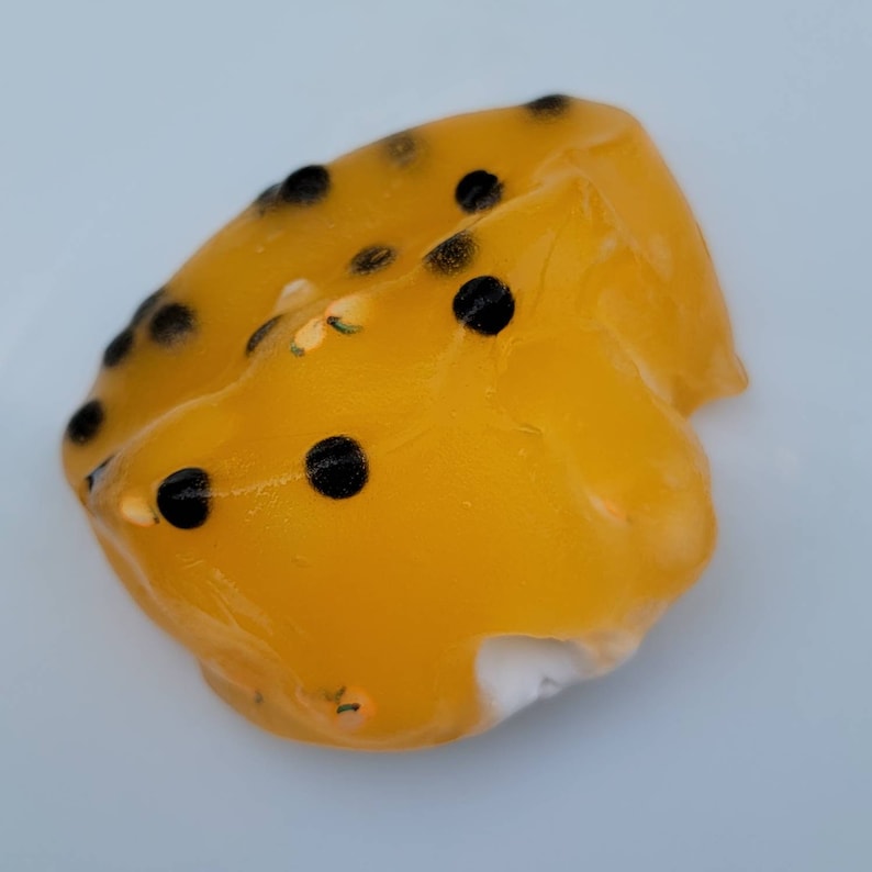 K&ouml;nnte beinhalten: Eine gelbe Passionsfrucht-Gelee mit schwarzen Samen. Die Gelee ist herzf&ouml;rmig und hat eine glatte, gl&auml;nzende Oberfl&auml;che.