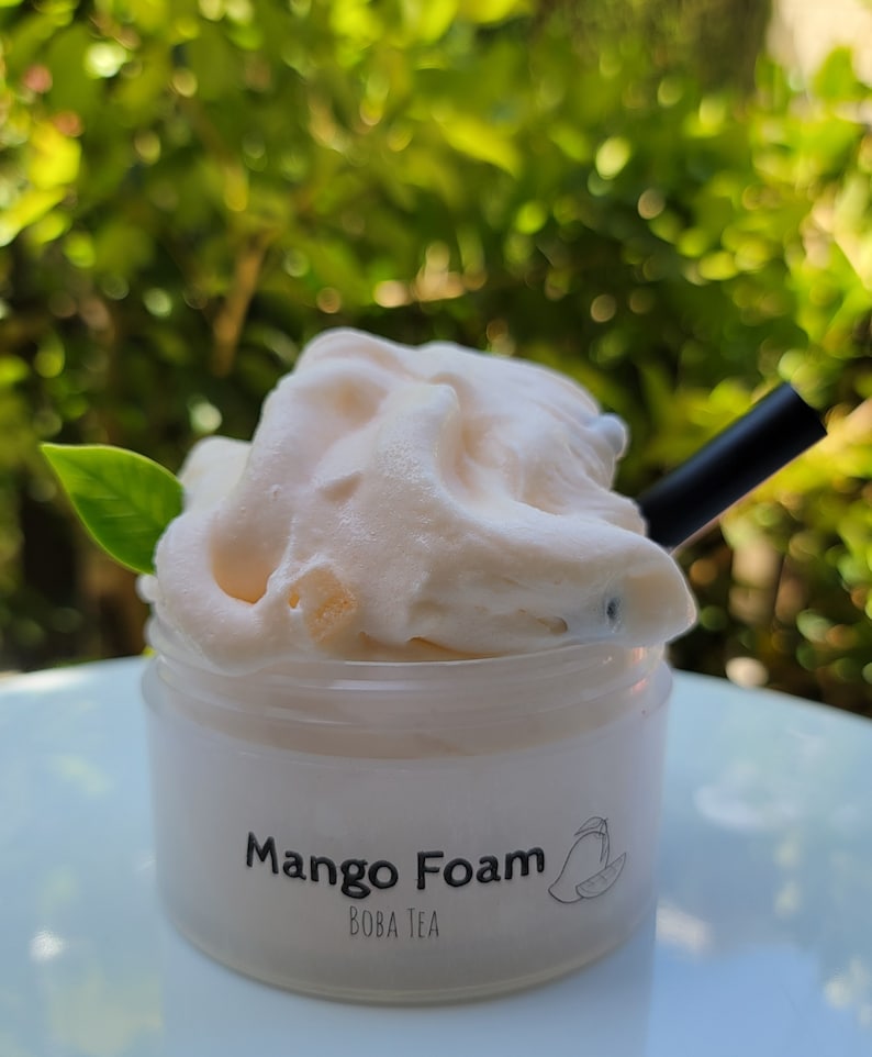 K&ouml;nnte beinhalten: Ein durchsichtiger Plastikbecher mit einem wei&szlig;en Deckel und einem wei&szlig;en Etikett mit der Aufschrift "Mango Foam Boba Tea". Der Becher ist mit einem hellrosa, geschlagenen Mangoschaum gef&uuml;llt. Ein schwarzer Strohhalm ragt aus dem Schaum.