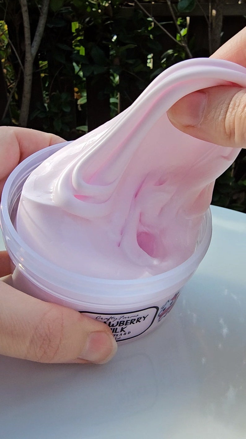 K&ouml;nnte beinhalten: Rosa Schleim in einem durchsichtigen Plastikbeh&auml;lter mit einem wei&szlig;en Etikett, auf dem "Crafty Farms Strawberry Milk" steht.