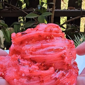 May include: Red slime with red glitter, being held by two hands.
