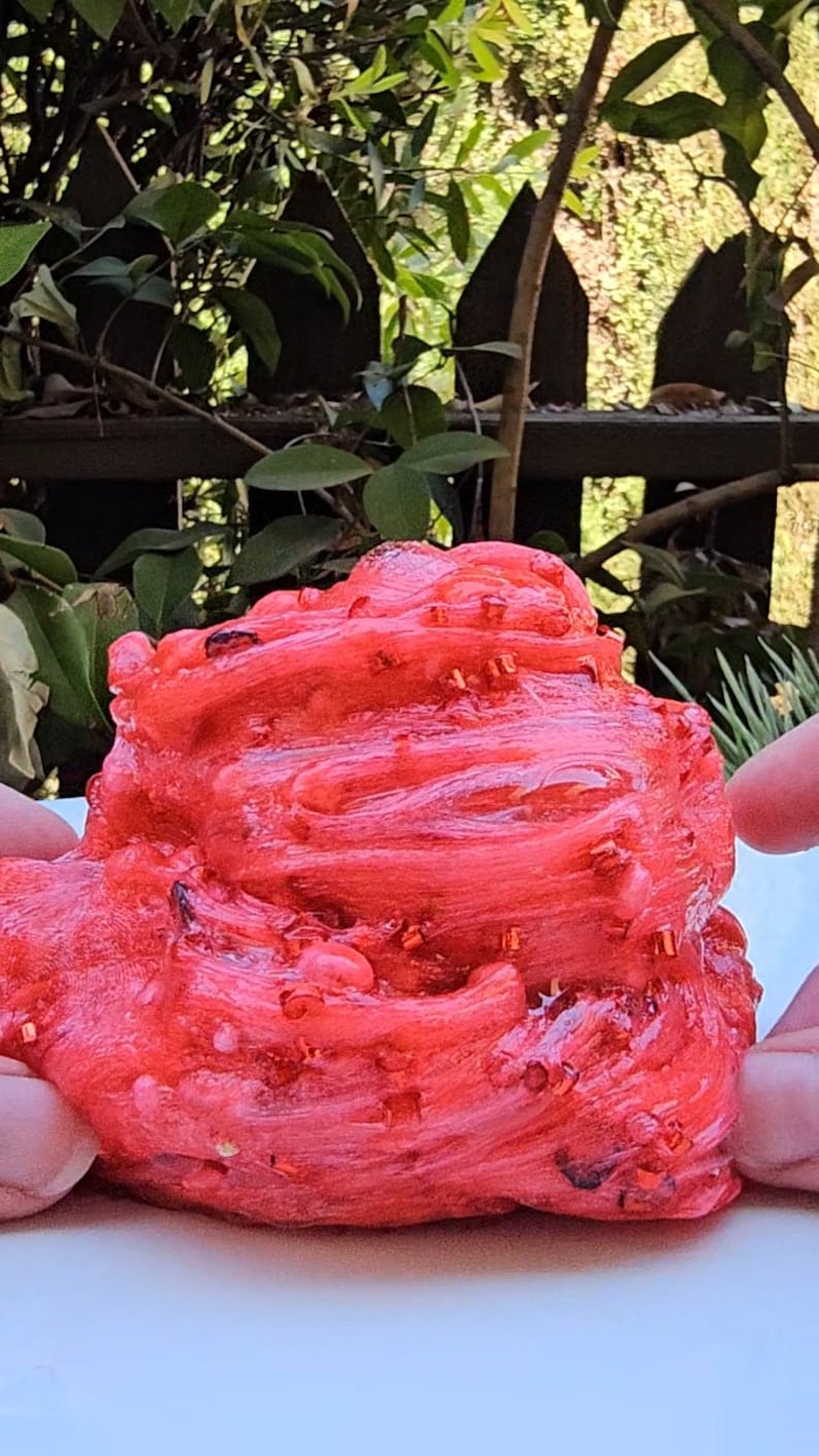May include: Red slime with red glitter, being held by two hands.