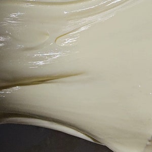May include: Close-up of a white, creamy slime being stretched and pulled. The slime is smooth and glossy, with a slightly translucent appearance.