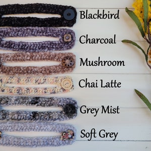 Op de afbeelding: Zes gebreide maskerverlengers in verschillende kleuren, waaronder blackbird, charcoal, mushroom, chai latte, grey mist en soft grey. Elke verlenging heeft twee knopen aan de uiteinden.