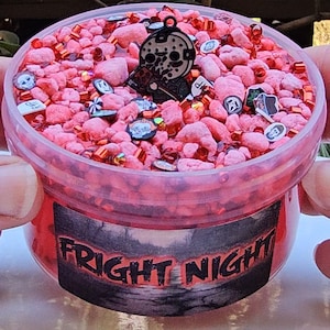 May include: A red slime with a black and white horror movie character charm, red and white sprinkles, and a label that says "Fright Night".