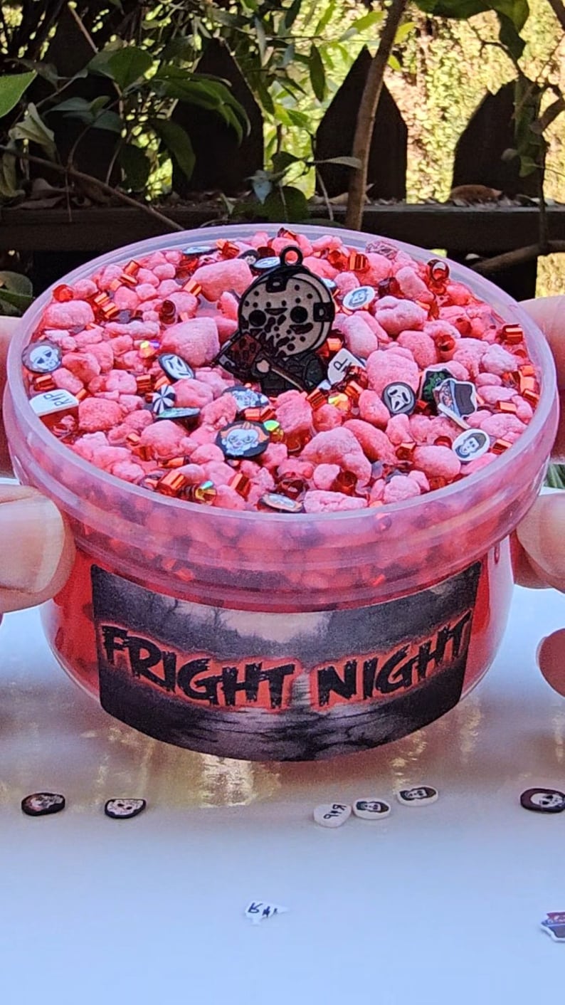 May include: A red slime with a black and white horror movie character charm, red and white sprinkles, and a label that says "Fright Night".